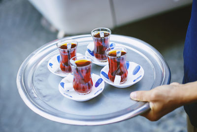 Midsection of person holding tea in serving tray