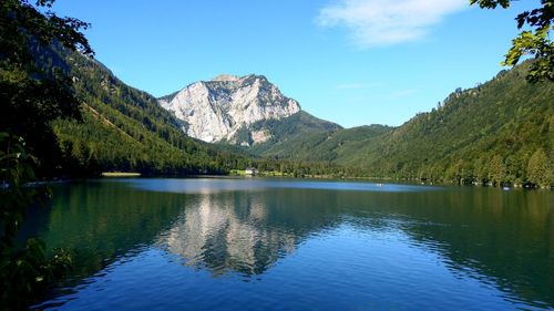 Scenic view of lake and mountains against blue sky