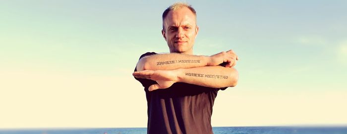 Portrait of man with tattoo standing against sky