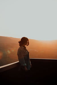 Side view of man standing against clear sky during sunset