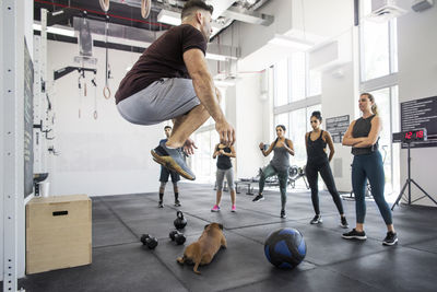 Instructor teaching athletes while dog lying in crossfit gym