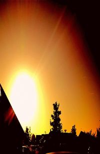 Low angle view of silhouette trees and buildings against sky during sunset