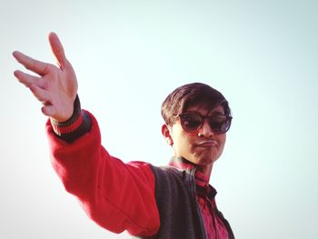 Portrait of man gesturing against clear sky