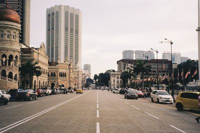 Traffic on city street by buildings against sky