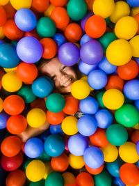 Directly above portrait of smiling playful boy amidst colorful ball pool