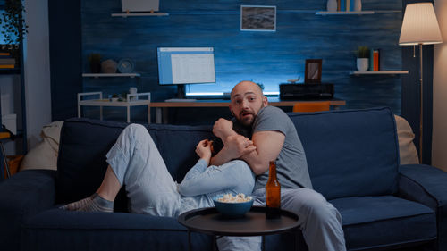 Scared couple sitting on sofa at home