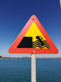 Close-up of yellow flag on sea against clear blue sky