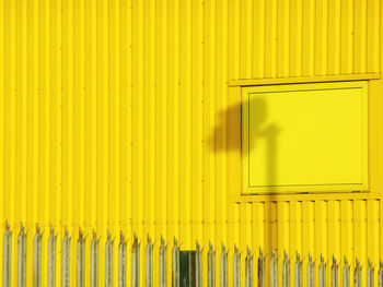 Shadow of security camera on yellow wall