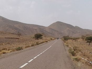 Empty road in desert against sky