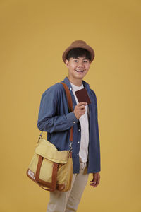 Portrait of smiling girl standing against yellow background