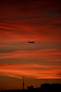 Low angle view of silhouette airplane against sky during sunset