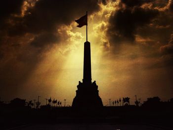 Low angle view of silhouette building against cloudy sky