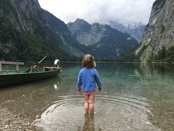 Rear view of woman looking at lake against mountains