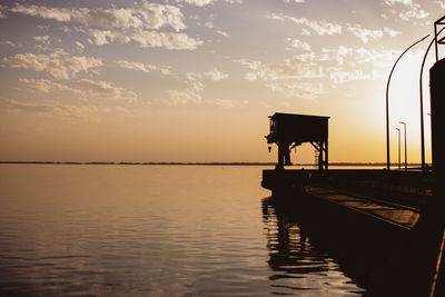 Scenic view of crane and its reflection on the sea under the sky during sunset