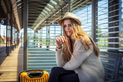 Portrait of girl wearing hat sitting on railroad station platform