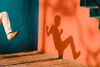Low section of man with shadow on wall