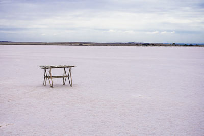 Empty table at beach against sky