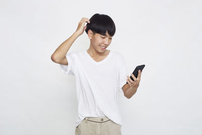 Young woman using mobile phone against white background