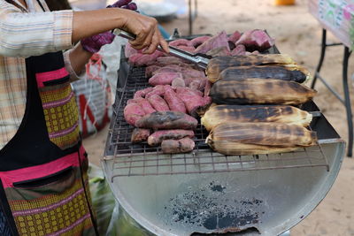 Midsection of man preparing food on barbecue grill