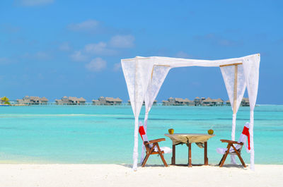 Deck chairs on beach against blue sky