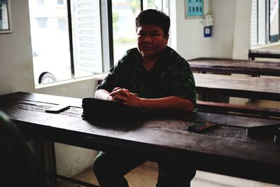 Portrait of young man sitting on table