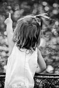 Rear view of little girl pointing towards lake