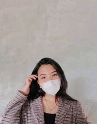 Portrait of beautiful young woman standing against wall