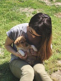 Rear view of woman with dog sitting on field