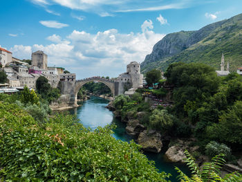 Arch bridge over river against cloudy sky