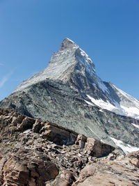 Low angle view of snowcapped mountain against blue sky