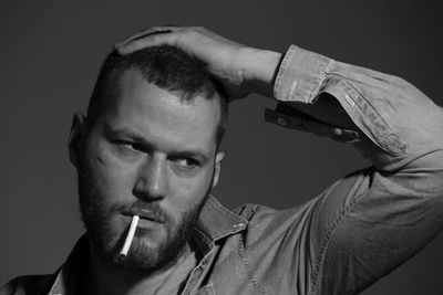 Close-up of man smoking cigarette against gray background