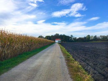 Road amidst field against sky