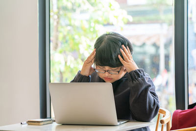 Portrait of man using mobile phone while sitting on table