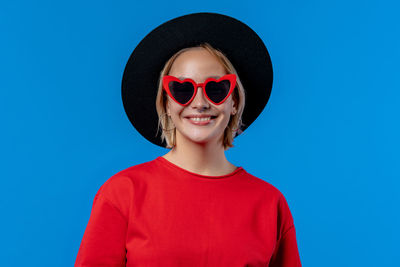 Portrait of woman wearing sunglasses against blue background