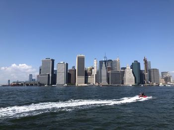 Modern buildings by sea against clear sky