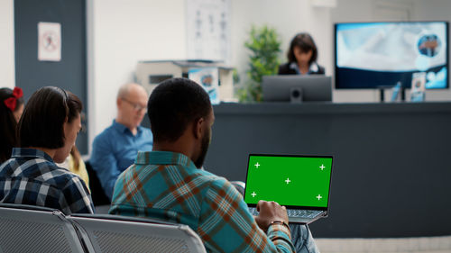 Rear view of man using digital tablet in office