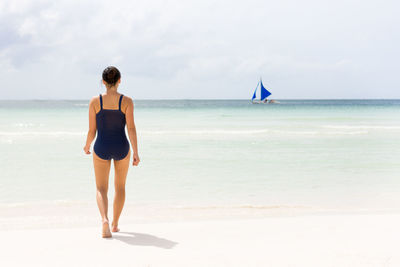 Rear view of woman in swimwear walking at beach
