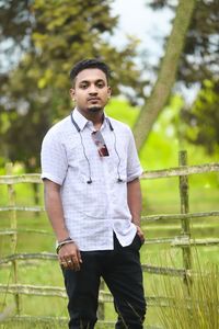 Portrait of young man standing against trees