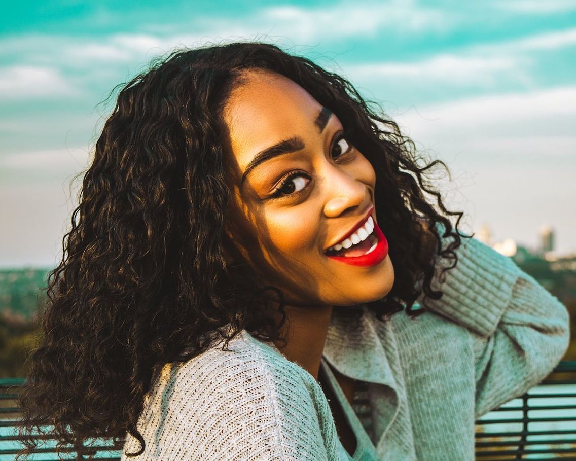 PORTRAIT OF SMILING YOUNG WOMAN OUTDOORS