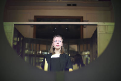 Low angle view of young woman looking up seen through hole