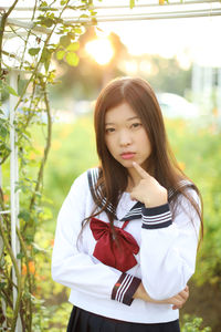 Portrait of young woman standing against plants