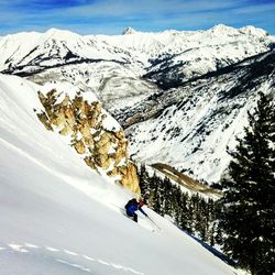 Man skiing on snowcapped mountain against sky