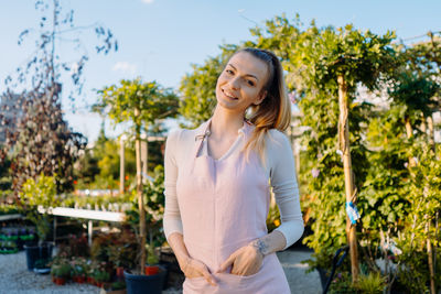 Portrait of young woman standing against trees