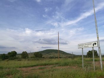 Road sign on landscape against sky