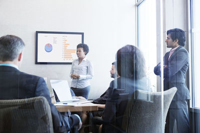 Businesswoman giving presentation to colleagues in conference room