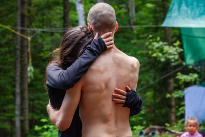 Rear view of shirtless man in forest