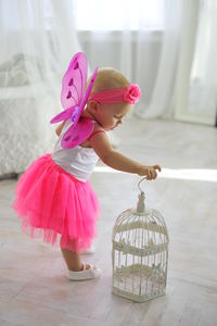 Cute girl playing with birdcage at home