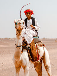 Bedouin young man on top of his camel in the desert 