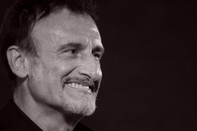 Close-up portrait of smiling man against black background