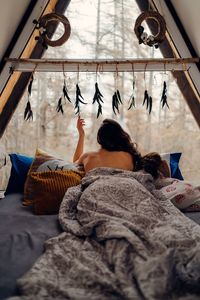 Rear view of woman relaxing on bed at home